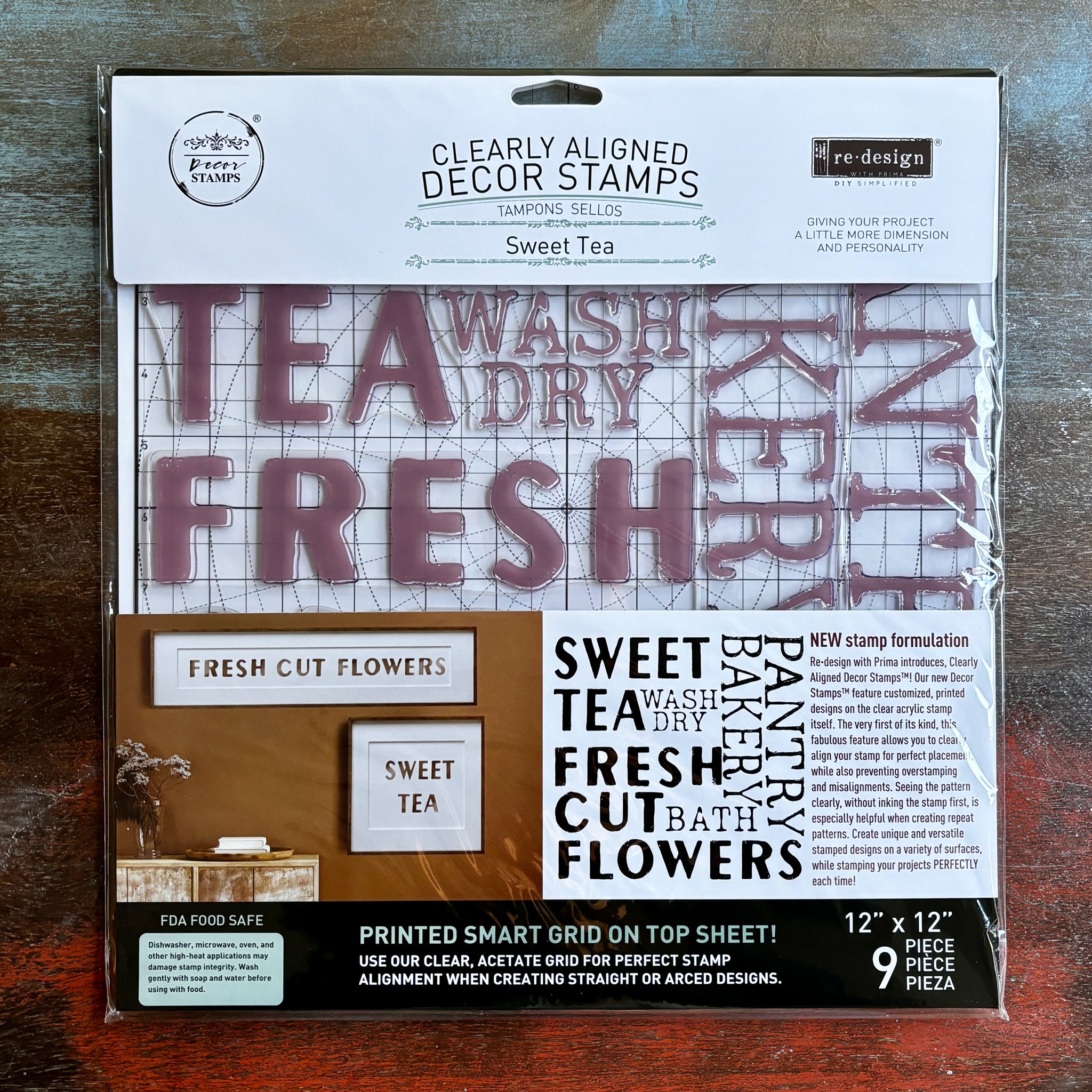 A package of ReDesign with Prima's Sweet Tea Clearly Aligned decor stamp is against a dark wood background.