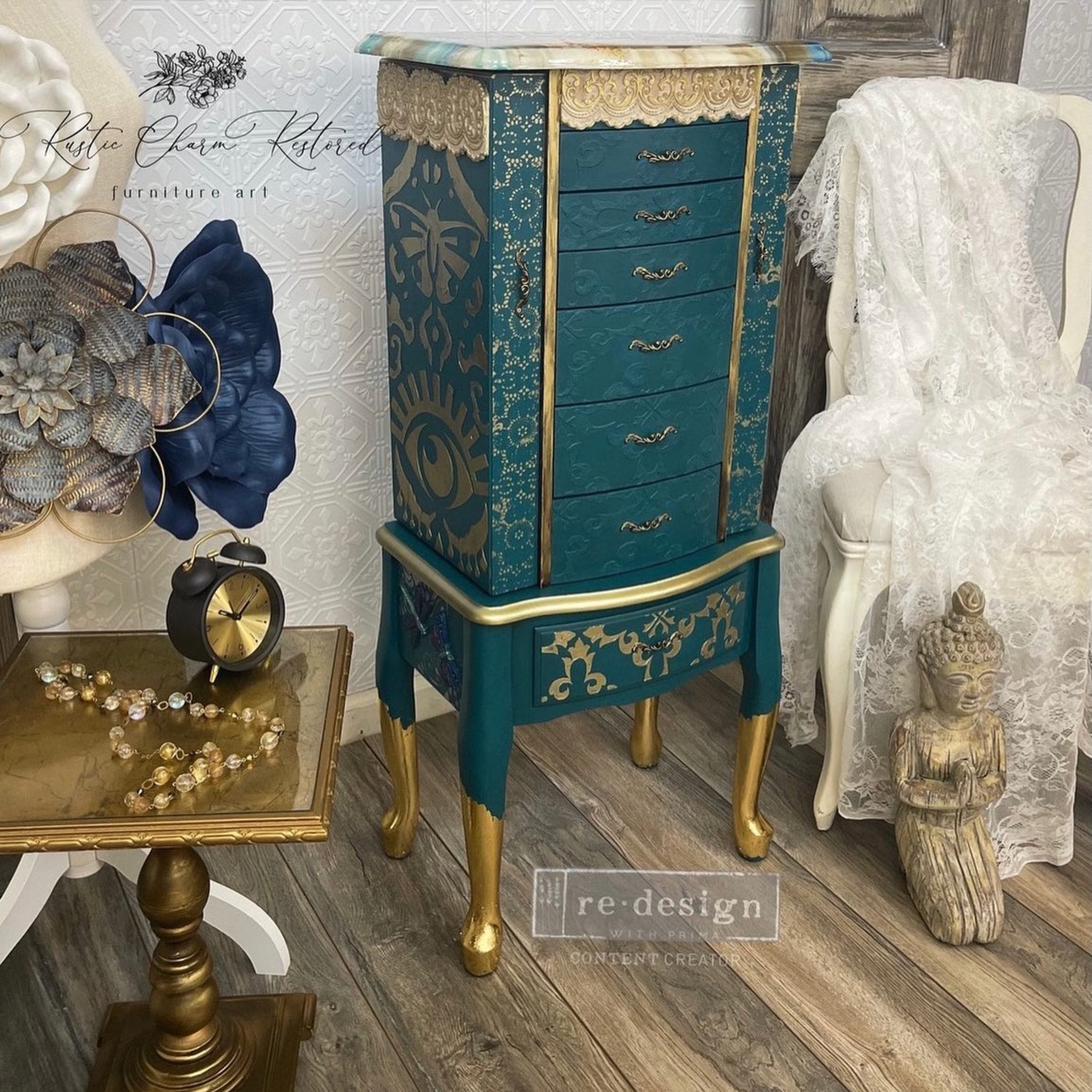 A vintage standing jewelry armoire refurbished by Rustic Charm Restored is painted teal with gold accents and features ReDesign with Prima's All Seeing Ikat stencil in gold on it.