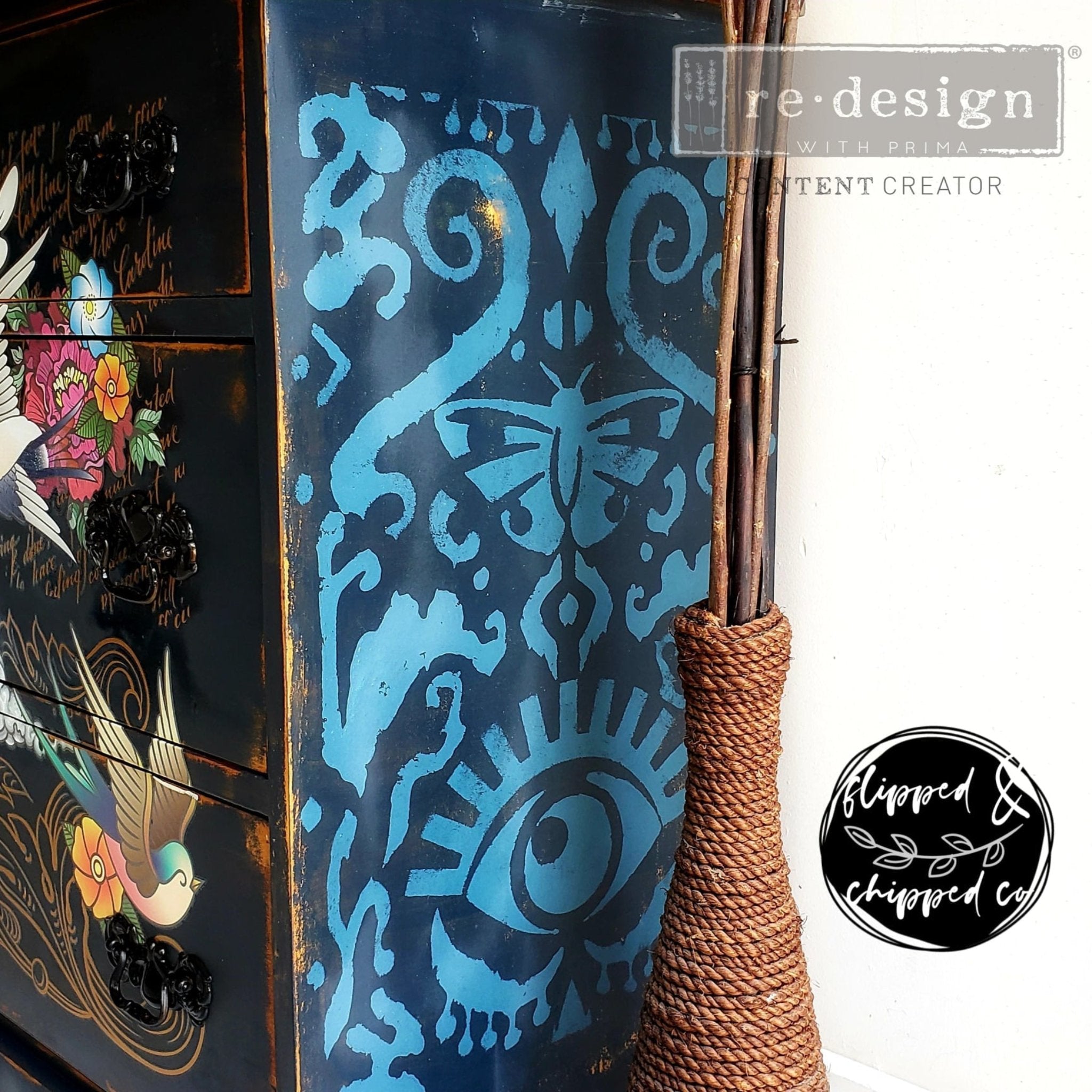 Close-up of a dresser refurbished by Flipped & Chipped is painted dark blue and features ReDesign with Prima's All Seeing Ikat stencil in light blue on the sides.