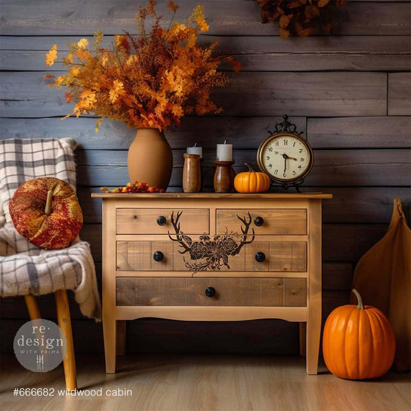 A natural stained wood dresser features ReDesign with Prima's Wildwood Cabin 3D stencil in black in the center of the front of the dresser.