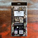 A package of ReDesign with Prima's Curious Journey tissue paper is against a dark wood background.