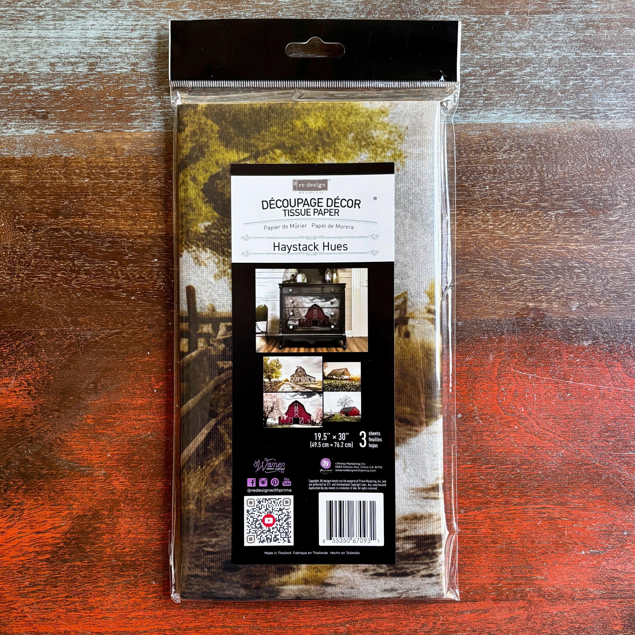 A package of ReDesign with Prima's Haystack Hues tissue paper is against a dark wood background.