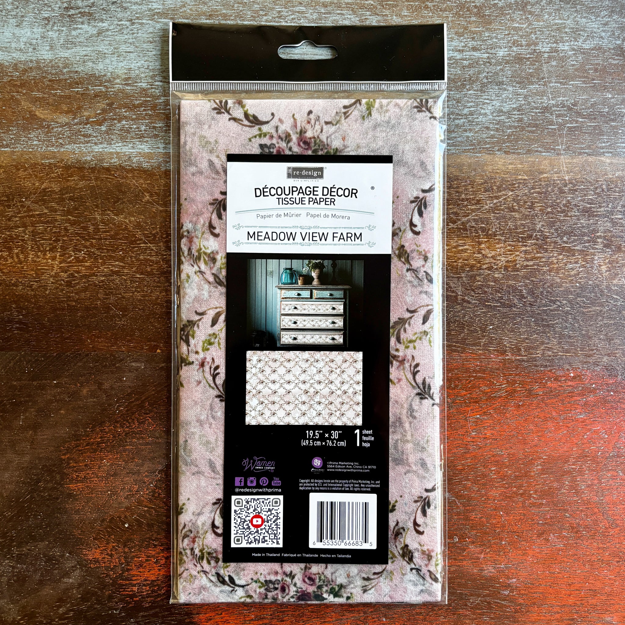 A package of ReDesign with Prima's Meadow View Farm tissue paper is against a dark wood background.