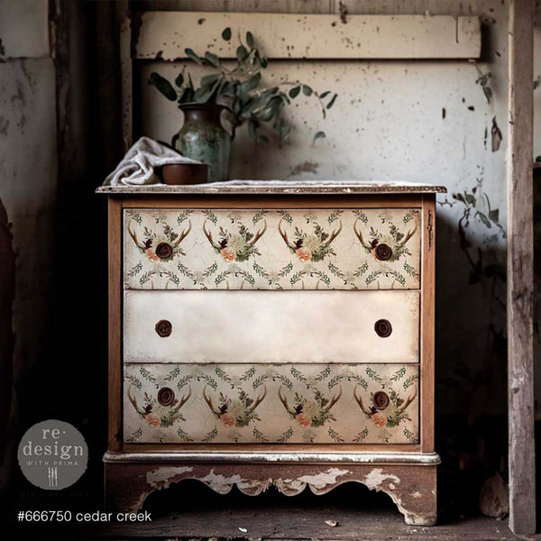 A vintage 3-drawer dresser is painted a weathered brown with cream colored drawers and features ReDesign with Prima's Cedar Creek tissue paper on its top and bottom drawer.