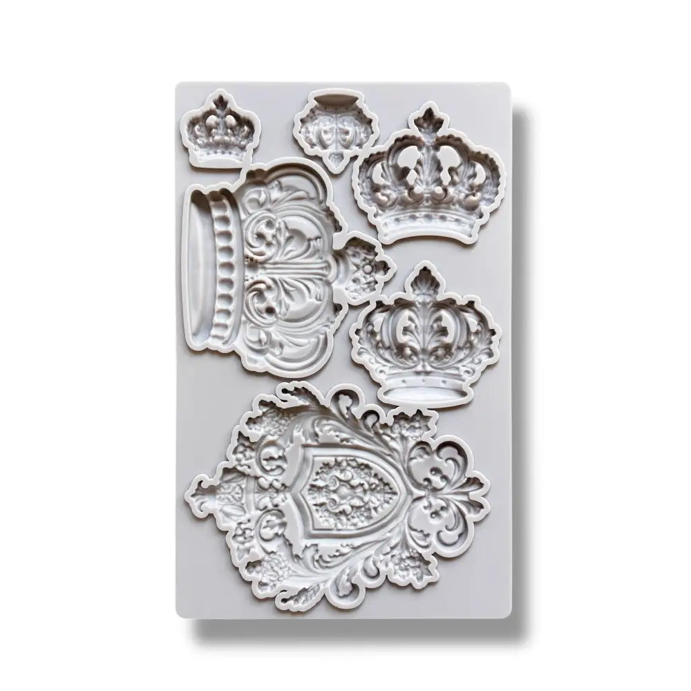 A light grey silicone mold featuring 5 varying size regal crowns and a family crest is against a white background.