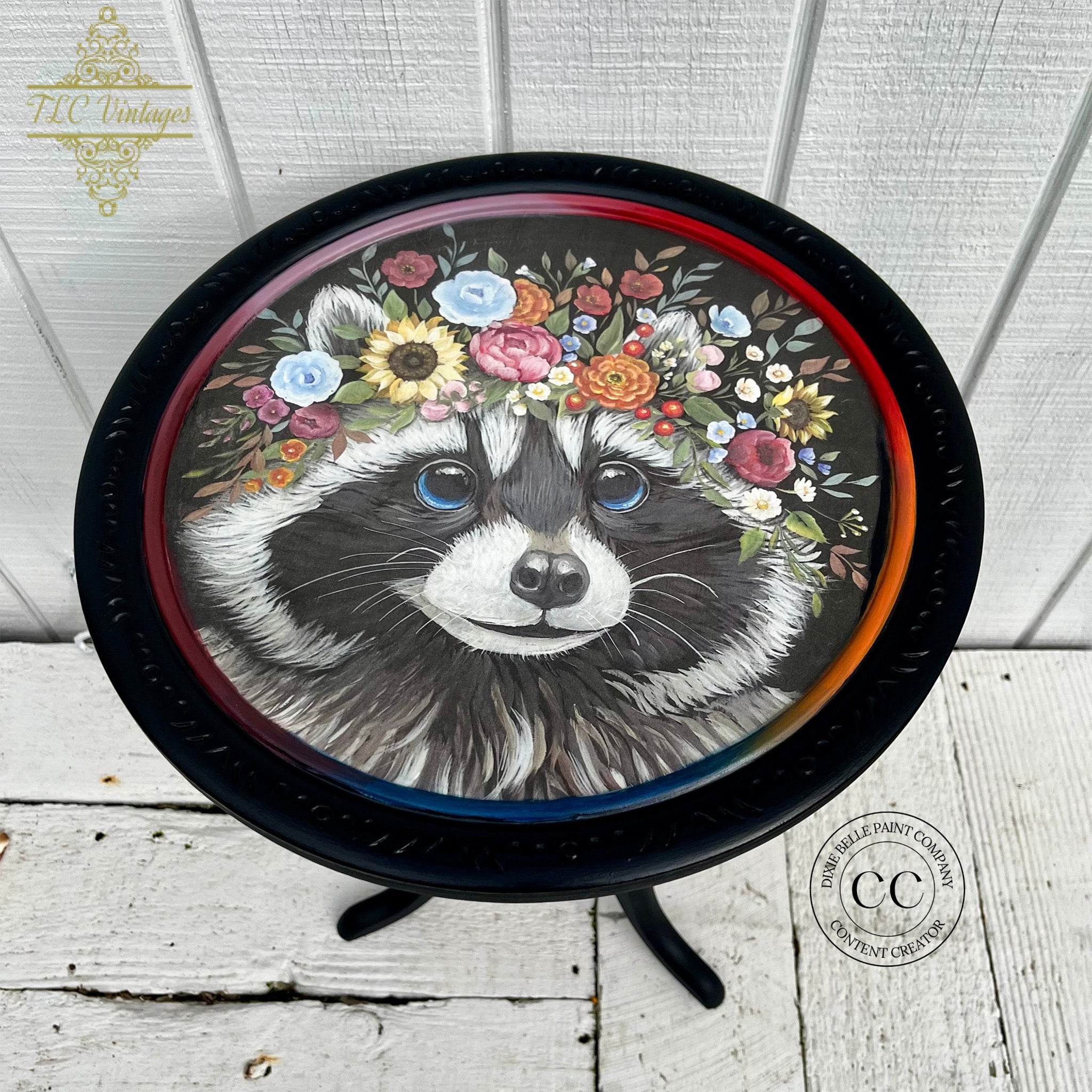 A round side table refurbished by TLC Vintages is painted black and features Belles & Whistles' Clever Raccoon rice decoupage paper on the top.