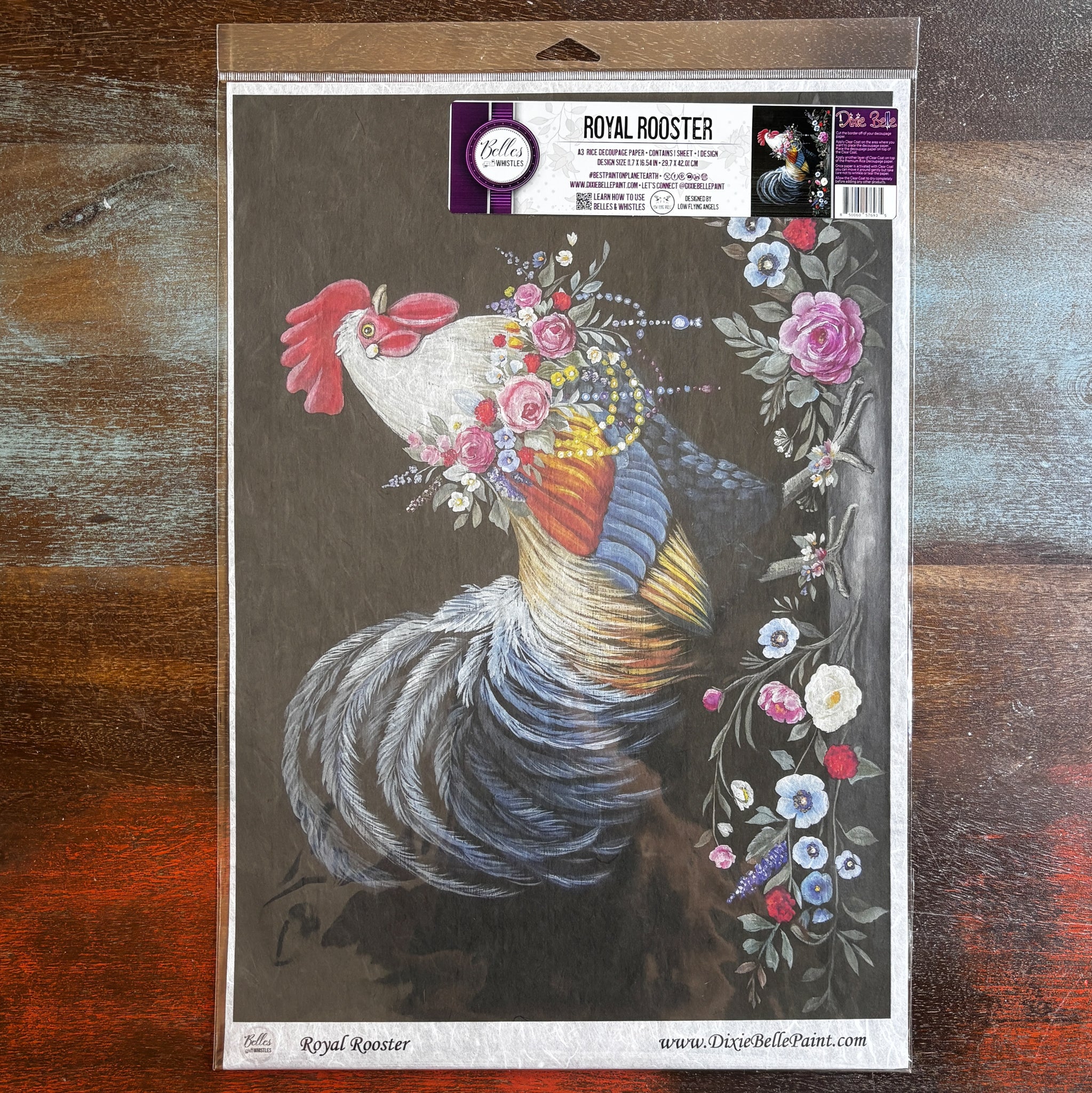 A package of Belles & Whistles' Royal Rooster A3 rice paper is against a dark wood background.