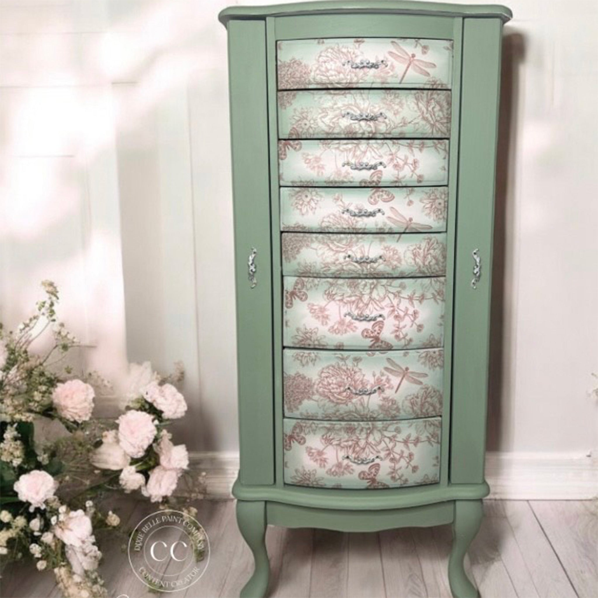 A vintage standing jewelry armoire is painted light sage green and features Belles & Whistles' Dragonfly Blooms on its front drawers.