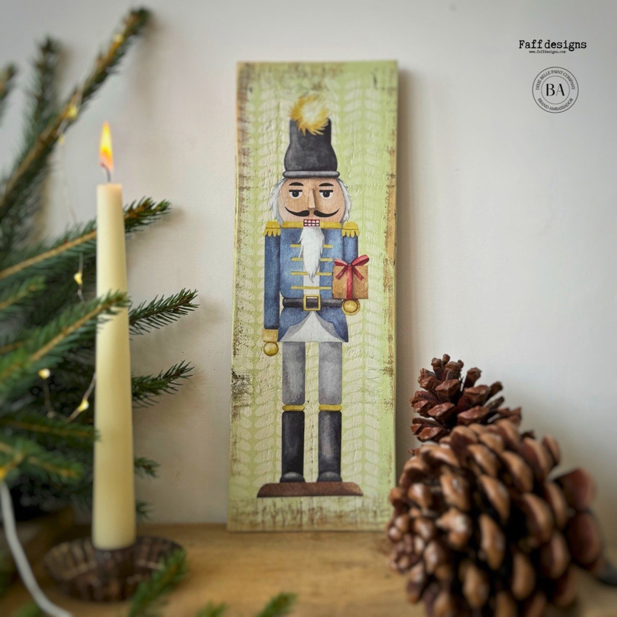 A tall woodcraft project painted light green by Faff Designs features a nutcracker in a black soldier hat and blue jacket from Belles & Whistles' Nutcracker small rub-on transfer on it.