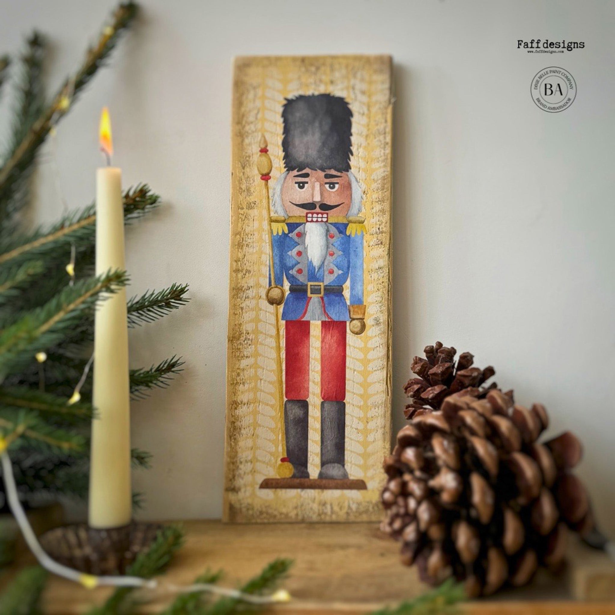 A tall woodcraft project painted mustard yellow by Faff Designs features a nutcracker in a black fuzzy hat and blue jacket from Belles & Whistles' Nutcracker small rub-on transfer on it.