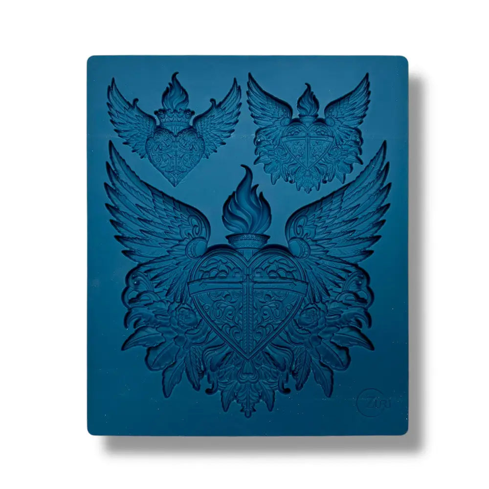 A blue silicone mold featuring 2 small and 1 large heart, each topped with flames and surrounded by wings, all nestled upon delicate flowers is against a white background.
