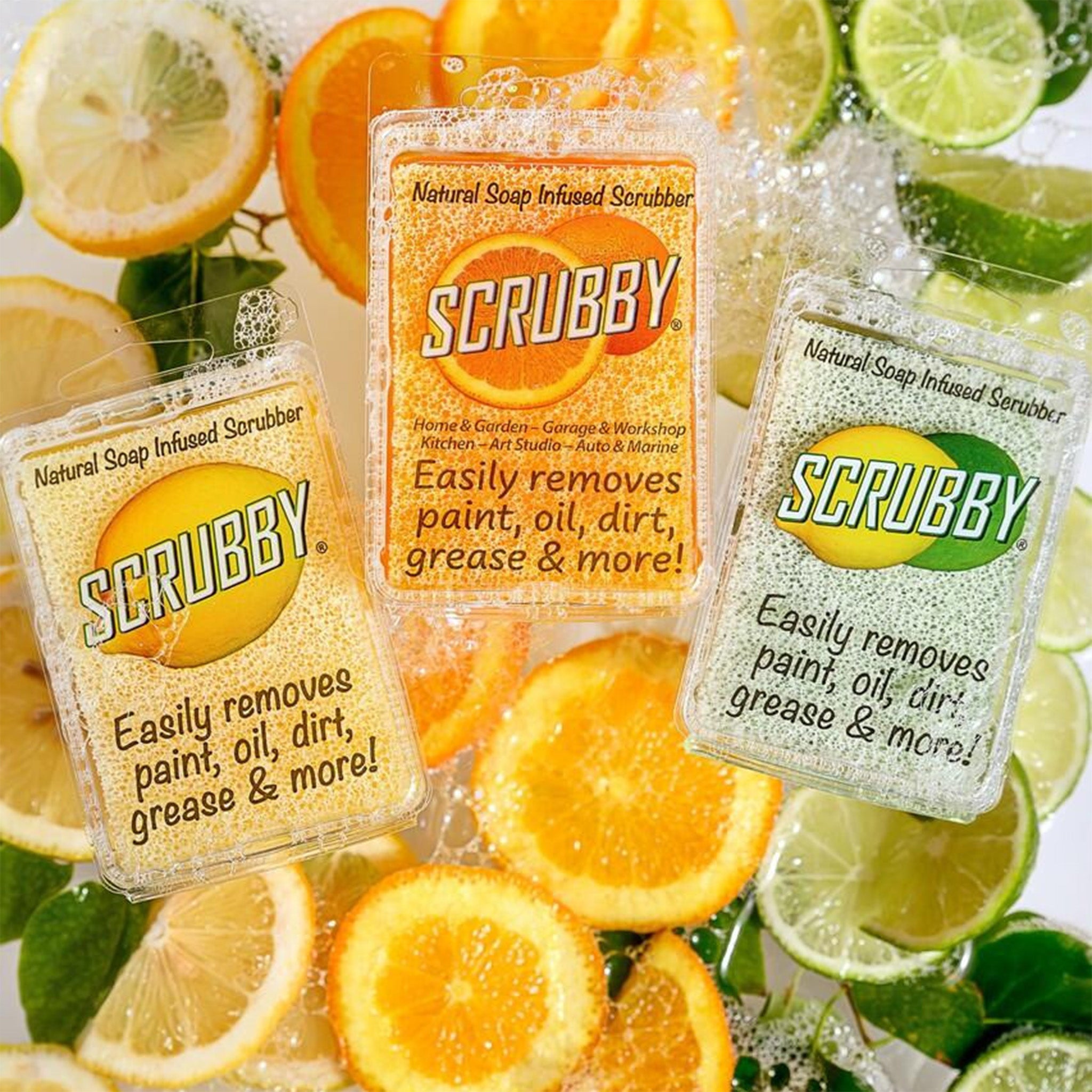 Three packages of Scrubby, a natural soap infused scrubber in scents of orange, lemon, and lime, are against a background of fresh sliced citrus fruits with soapy bubbles.