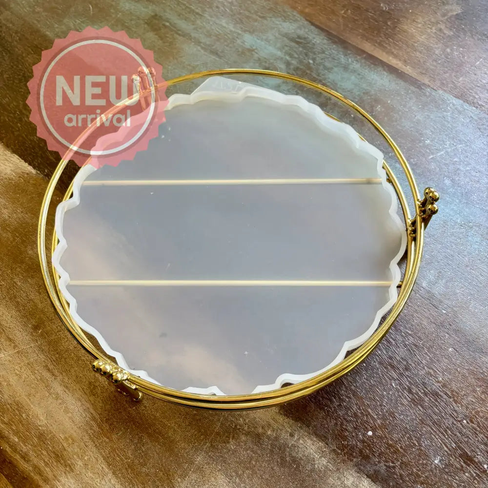 A silicone mold to make a 10.62" resin tray and a gold stand are against a wood background.