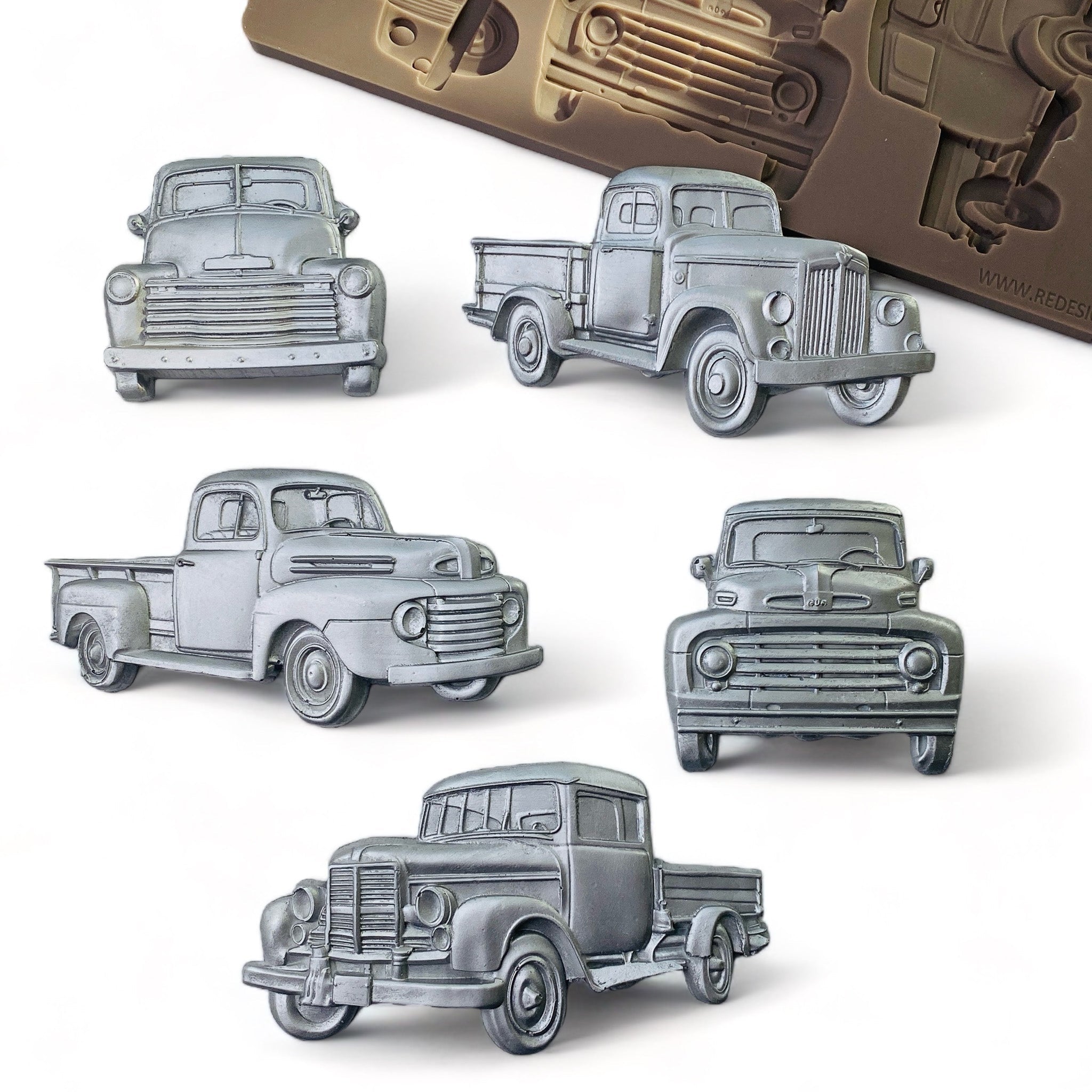 Silver colored silicone mold castings of 5 vintage farm trucks are against a white background.