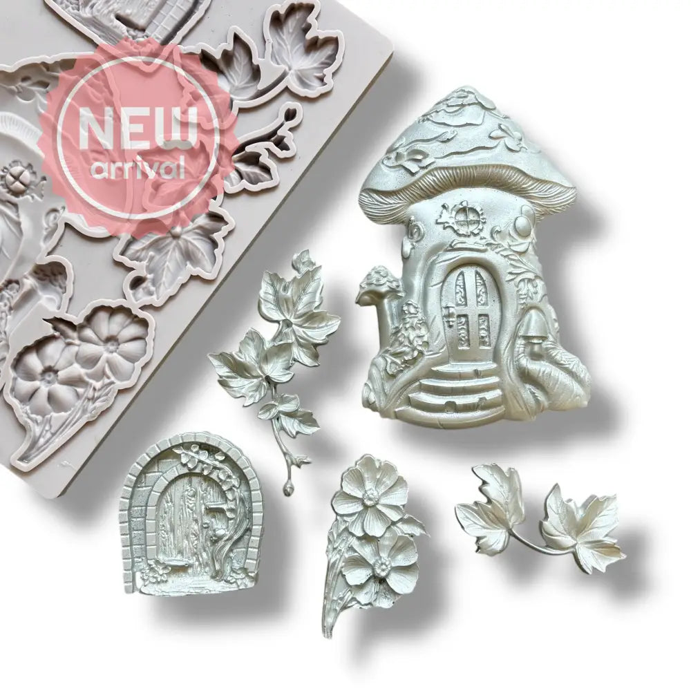 A light grey silicone mold and silver colored castings of a mushroom fairy house, a hobbit style door, and leaves and flowers are against a white background.