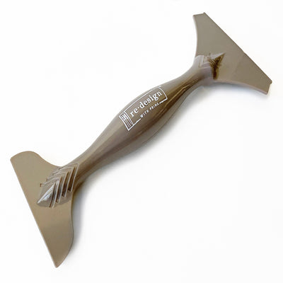 A double-ended brown furniture decal transfer that reads ReDesign with Prima on the handle is against a white background.