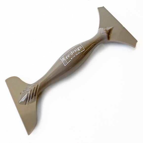 A double-ended brown furniture decal transfer that reads ReDesign with Prima on the handle is against a white background.