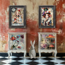 Two picture frames featuring Whimsykel's Allison Wonderland and Mattie Hadder Due tissue paper are hanging above 2 white 3-drawer dressers with Wonderland inspired designs on the drawers.