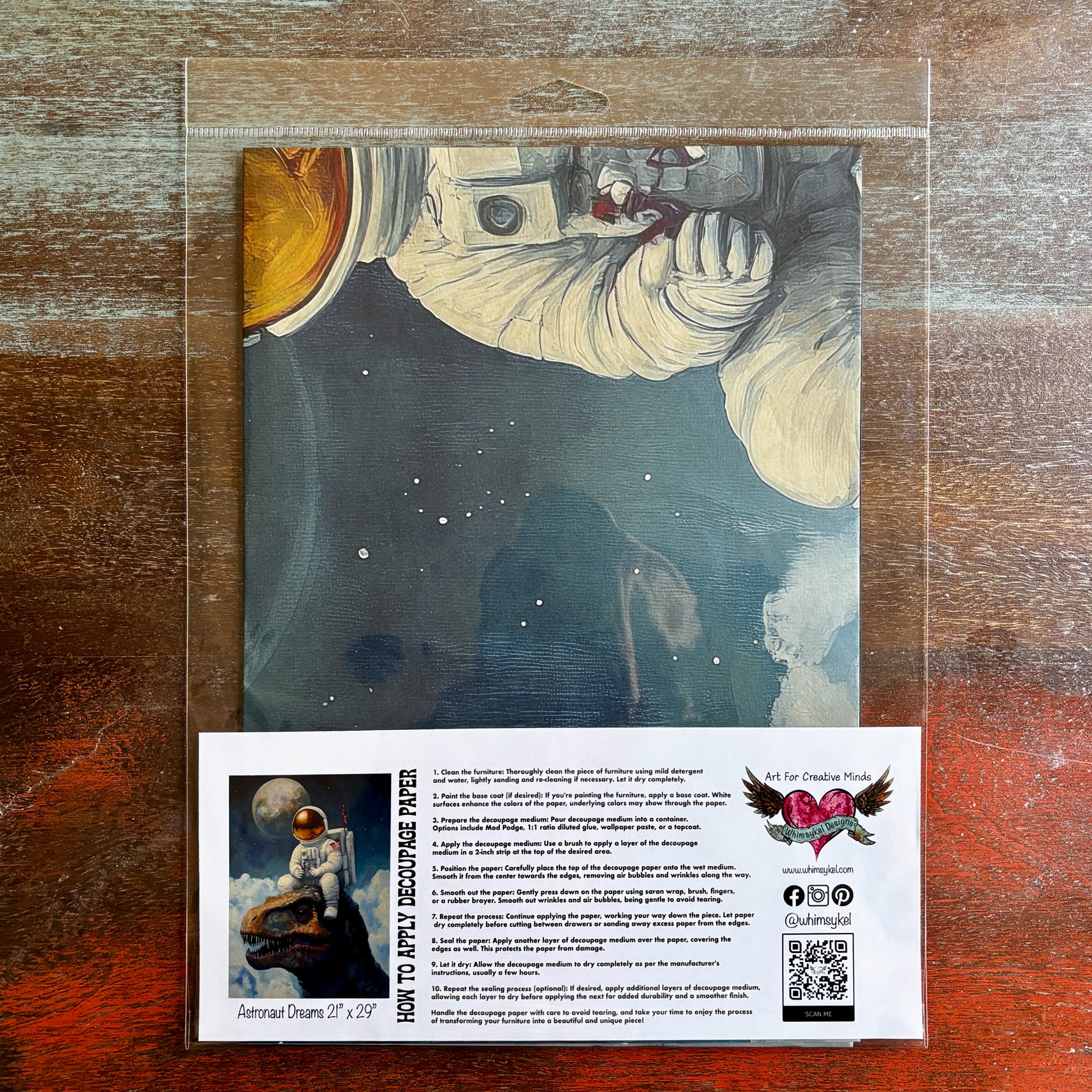 A package of Whimsykel's Astronaut Dreams tissue paper is against a dark wood background.