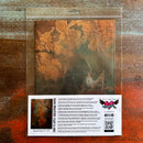A package of Whimsykel's Baroque Patina tissue paper is against a dark wood background.