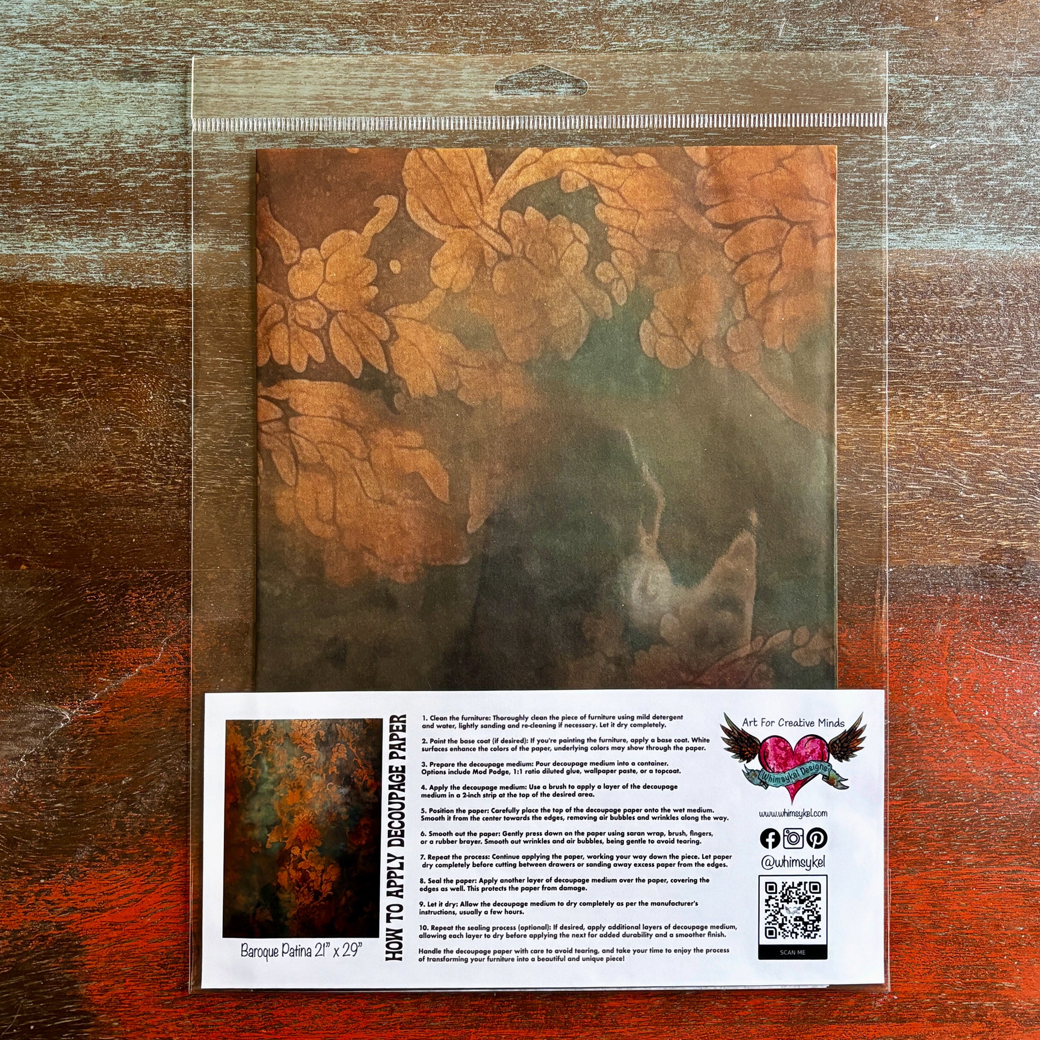 A package of Whimsykel's Baroque Patina tissue paper is against a dark wood background.