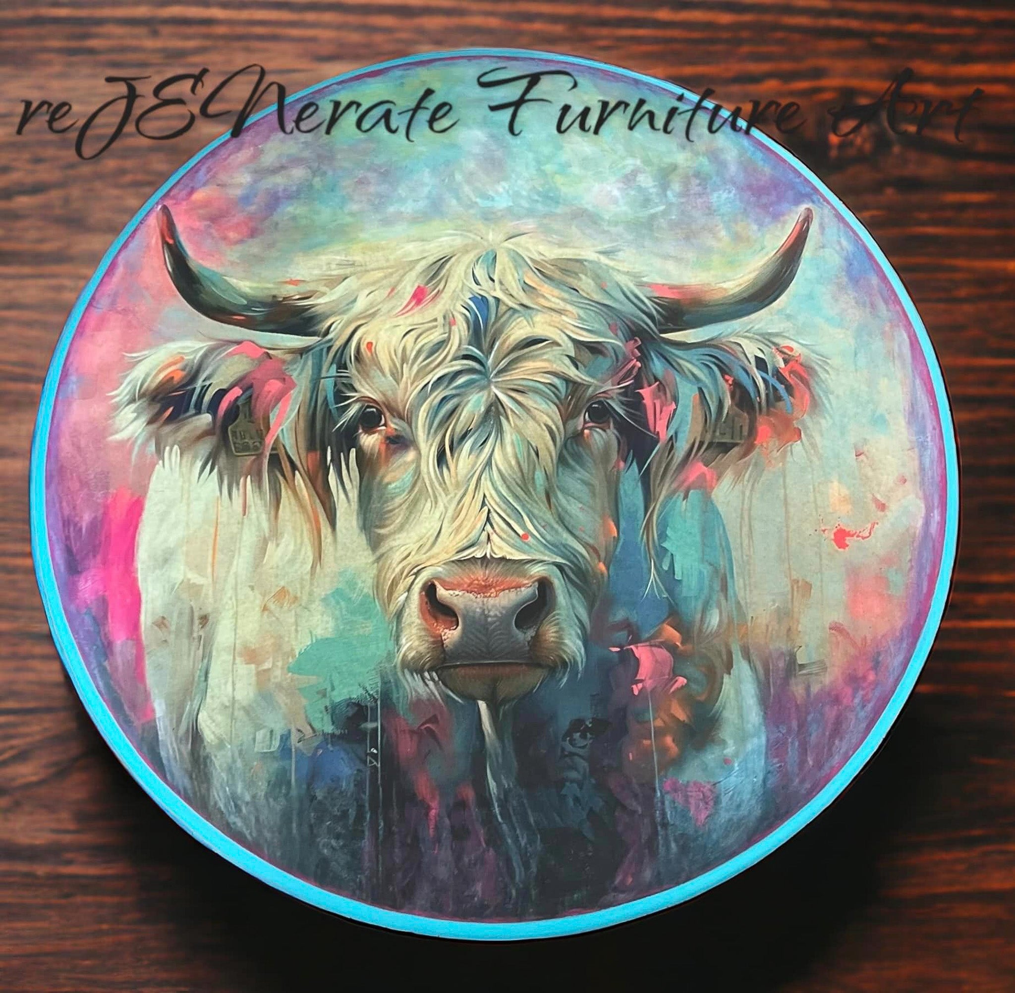 A round wood craft created by reJENerate Furniture Art is against a wood background and features Whimsykel's Bessie Blue Cow tissue paper on it.
