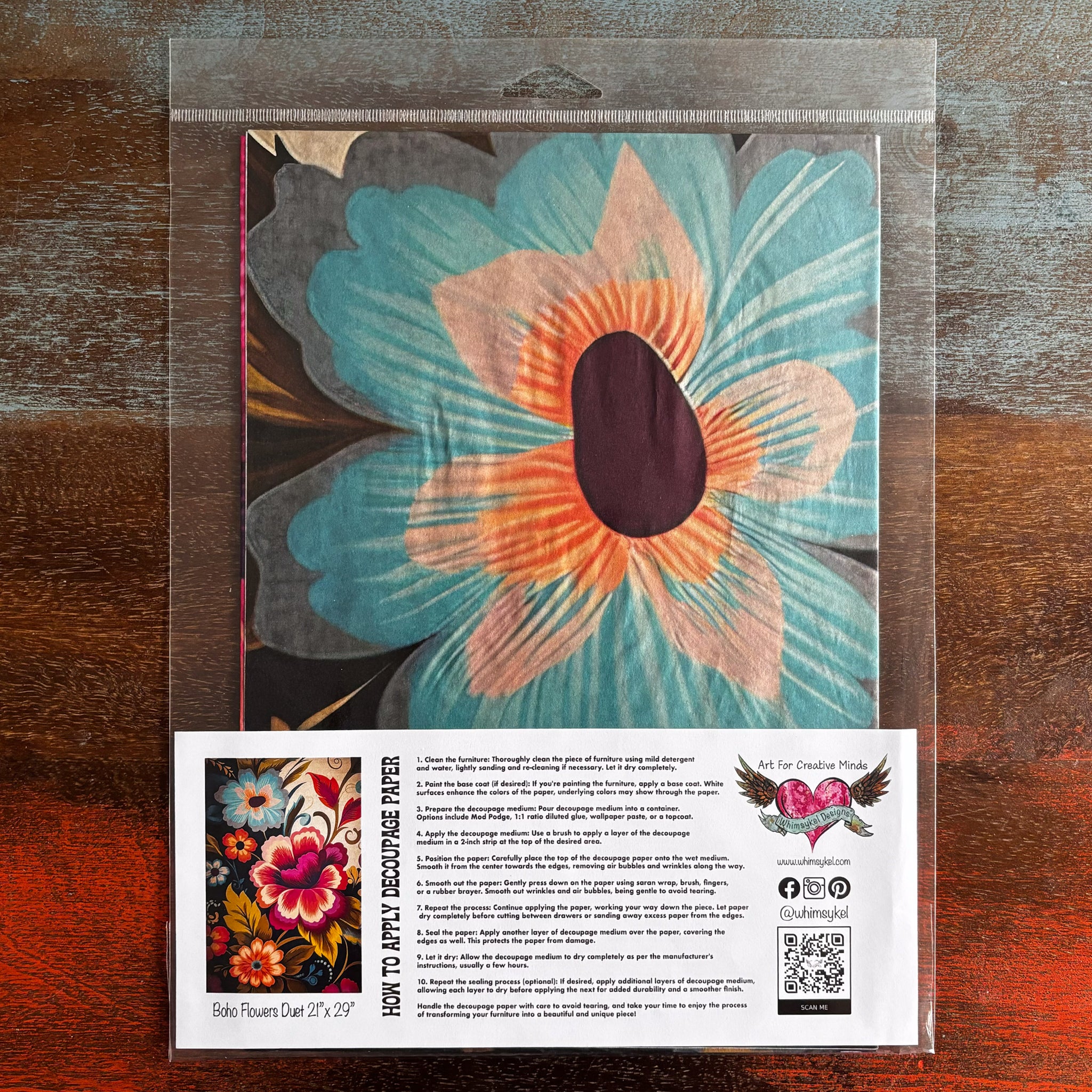 A package of Whimsykel's Boho Flowers Duet tissue paper is against a dark wood background.