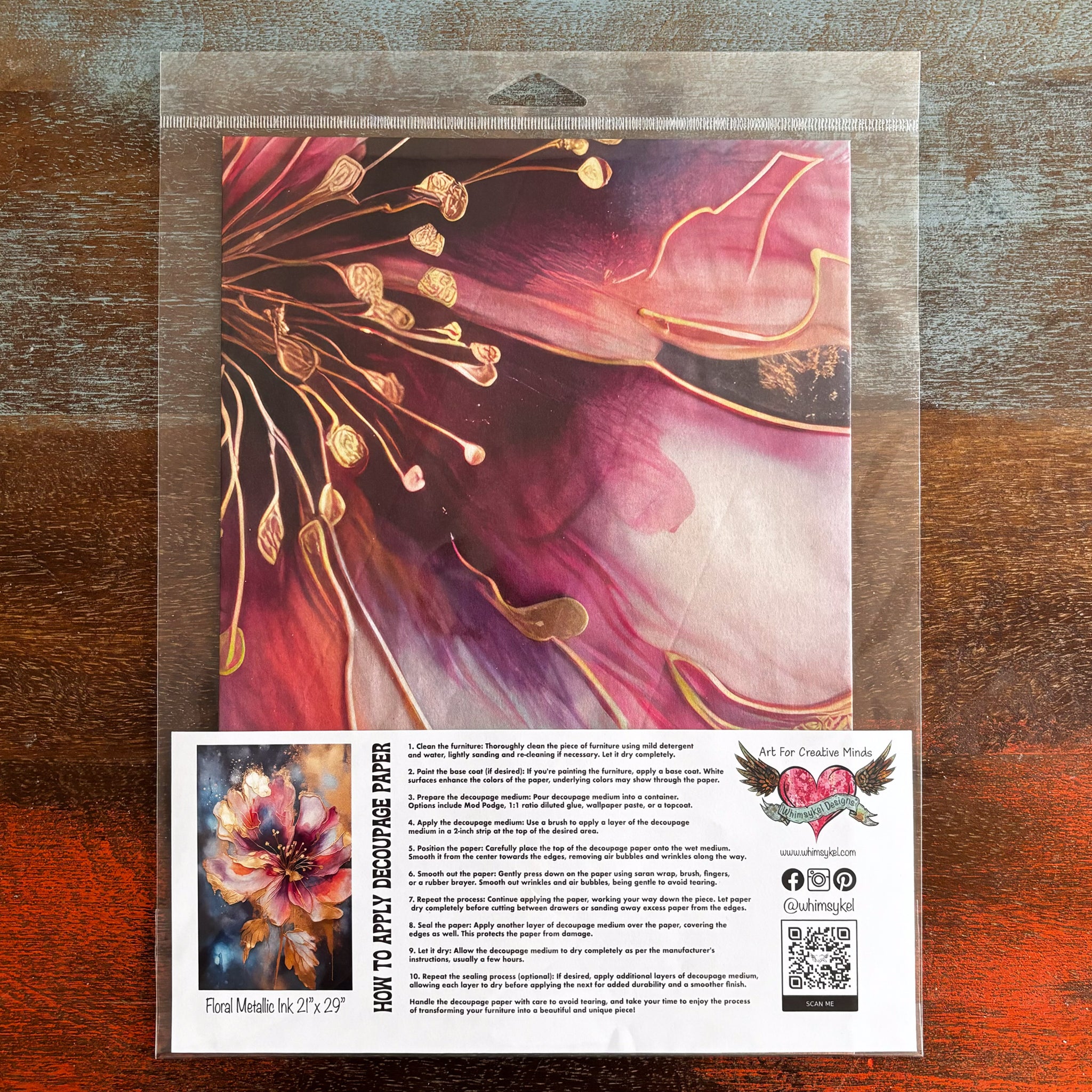 A package of Whimsykel's Floral Metallic Ink tissue paper is against a dark wood background.