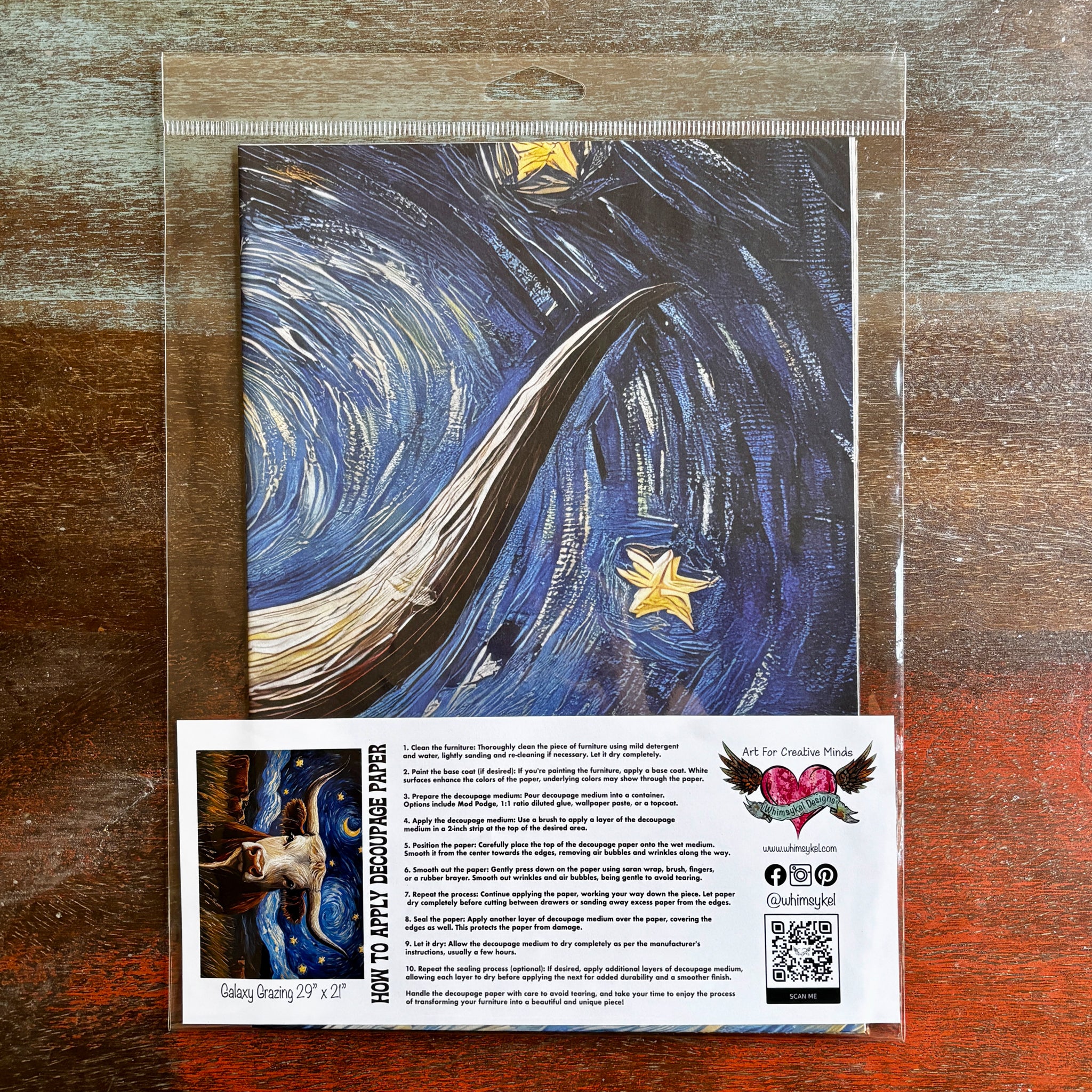 A package of Whimsykel's Galaxy Grazing tissue paper is against a dark wood background.