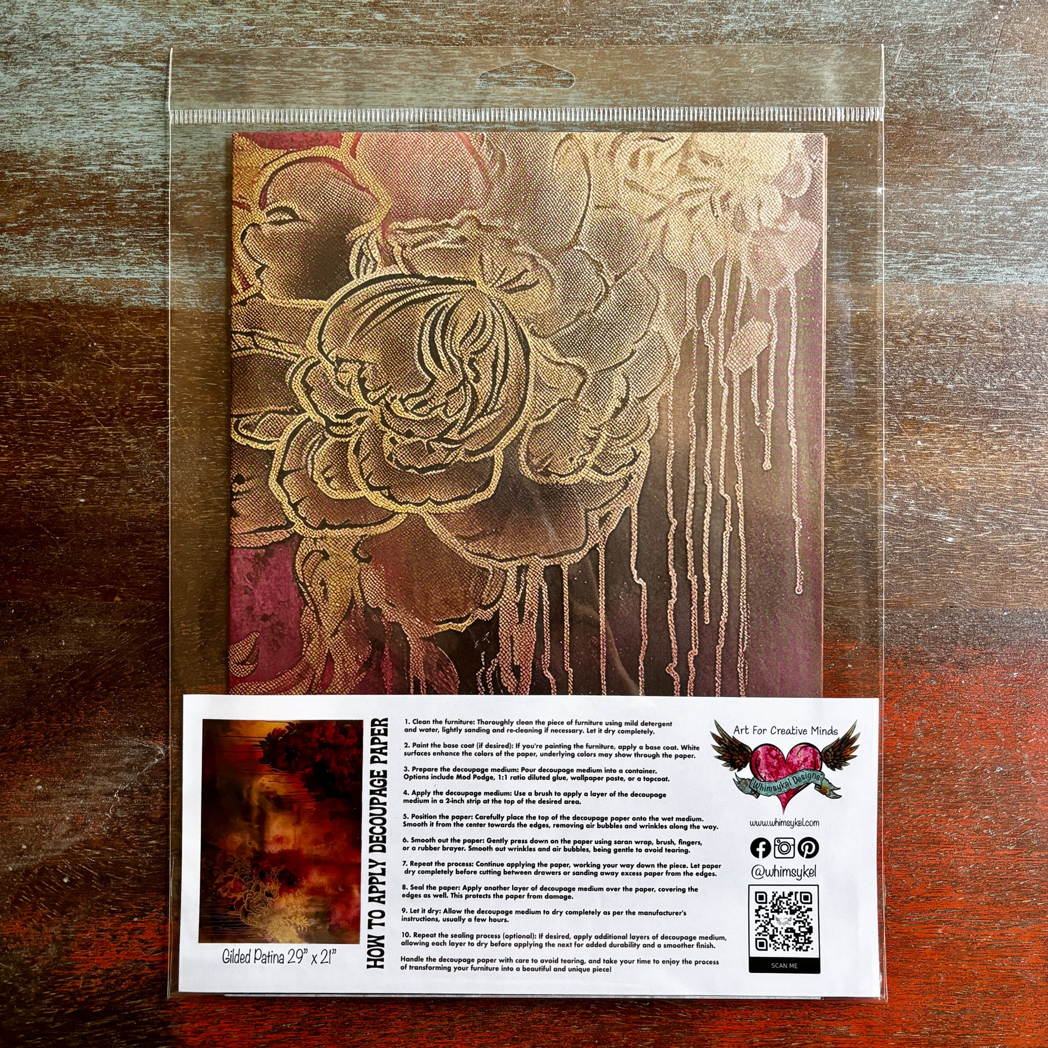 A package of Whimsykel's Gilded Patina tissue paper is against a dark wood background.