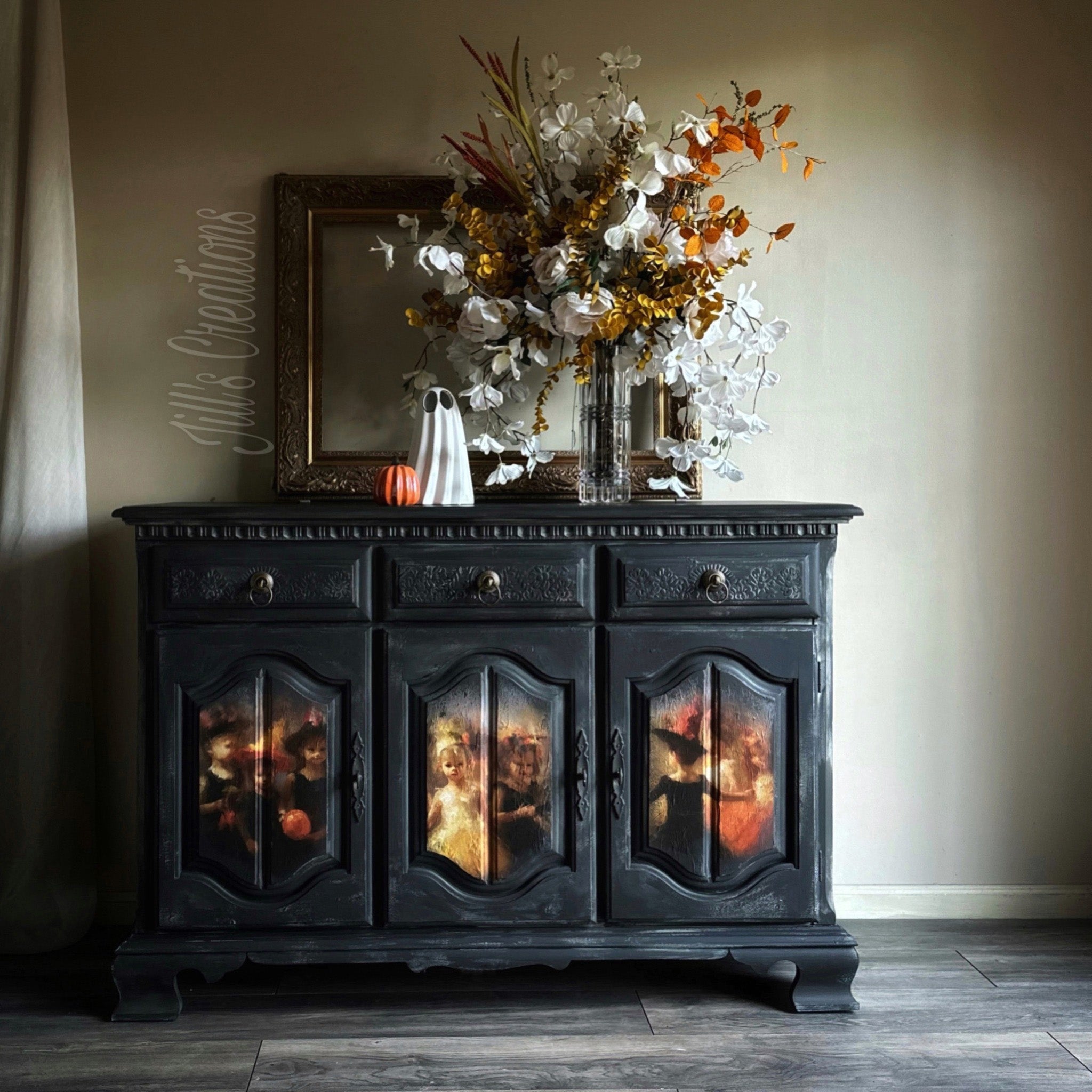 A vintage buffet table refurbished by Jill's Creations is painted black and features Whimsykel's Halloween Recital tissue paper on its 3 doors.