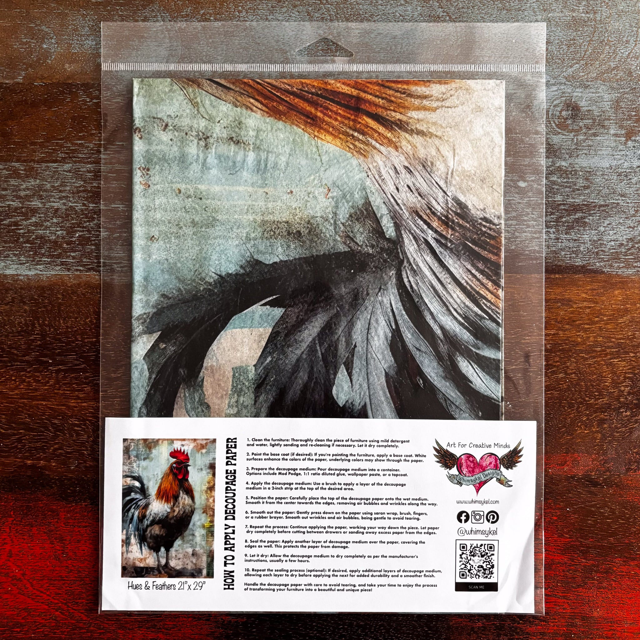 A package of Whimsykel's Hues & Feathers tissue paper is against a dark wood background.