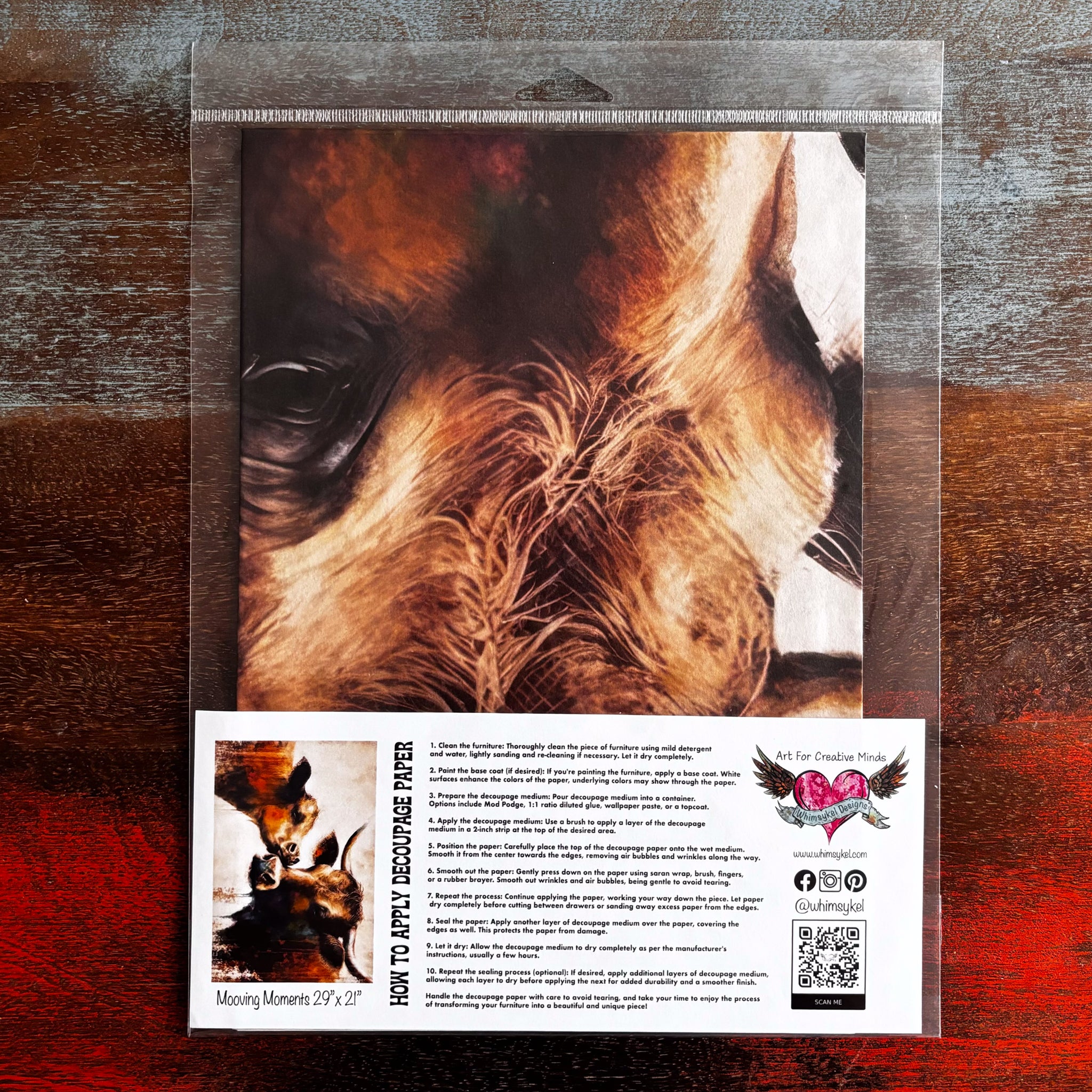 A package of Whimsykel's Mooving Moments tissue paper is against a dark wood background.