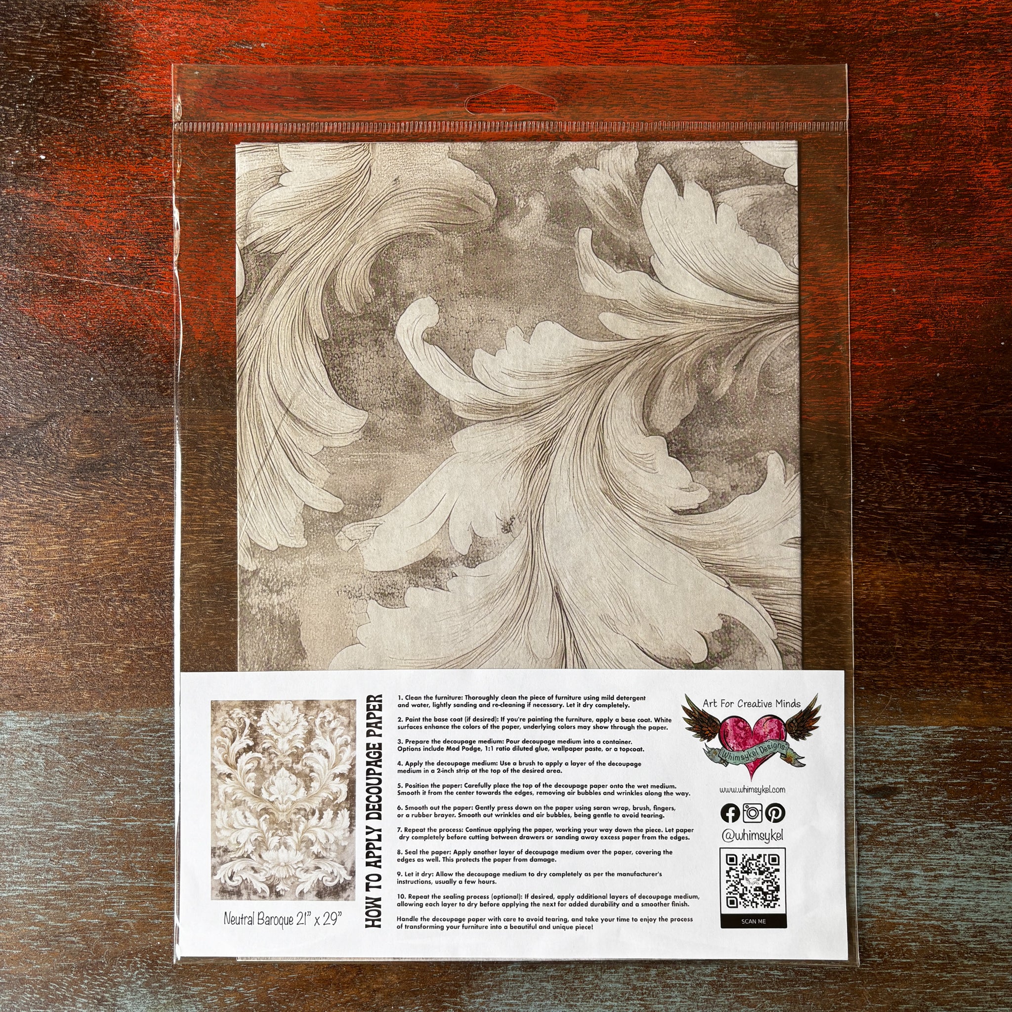 A package of Whimsykel's Neutral Baroque tissue paper is against a dark wood background.