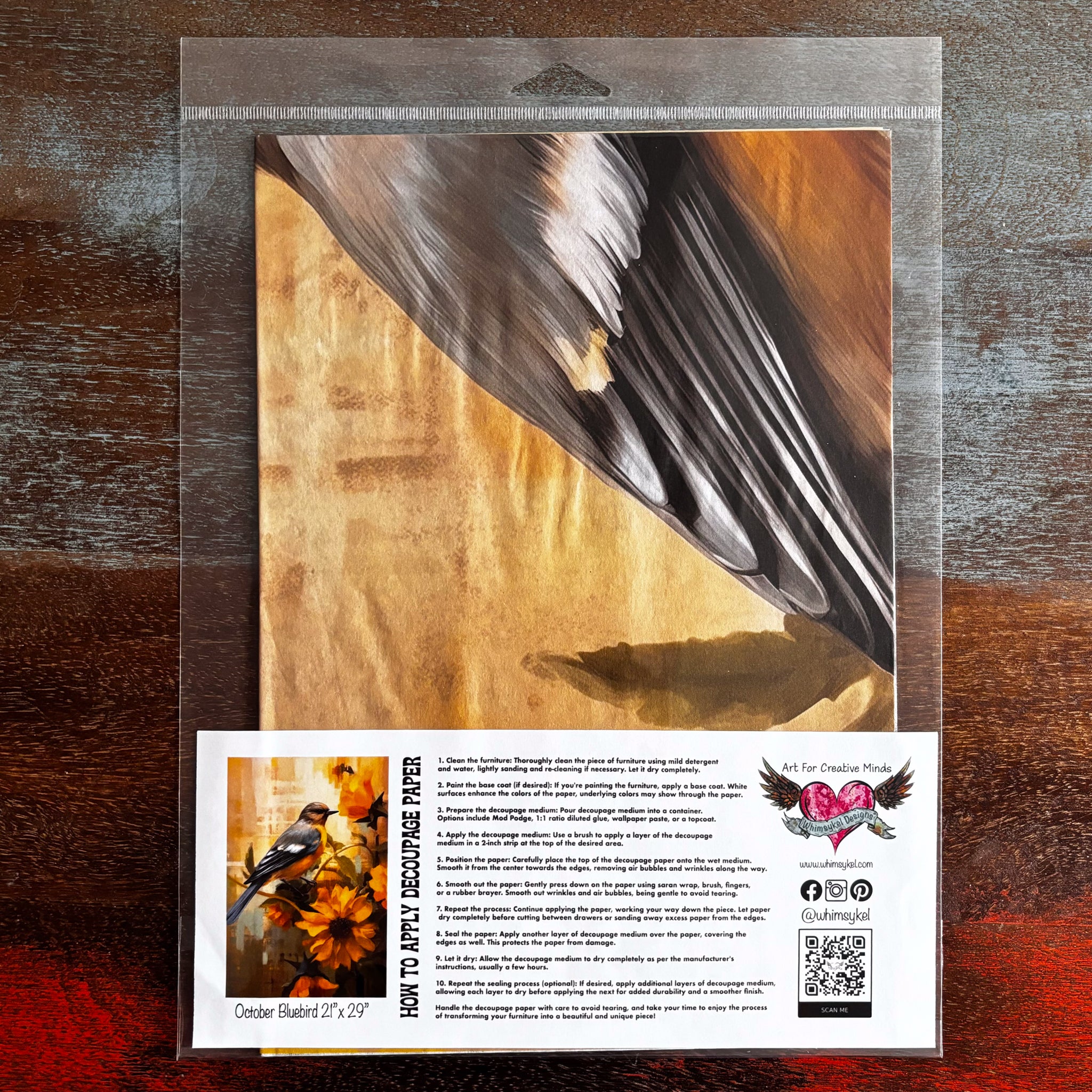 A package of Whimsykel's October Bluebird tissue paper is against a dark wood background.