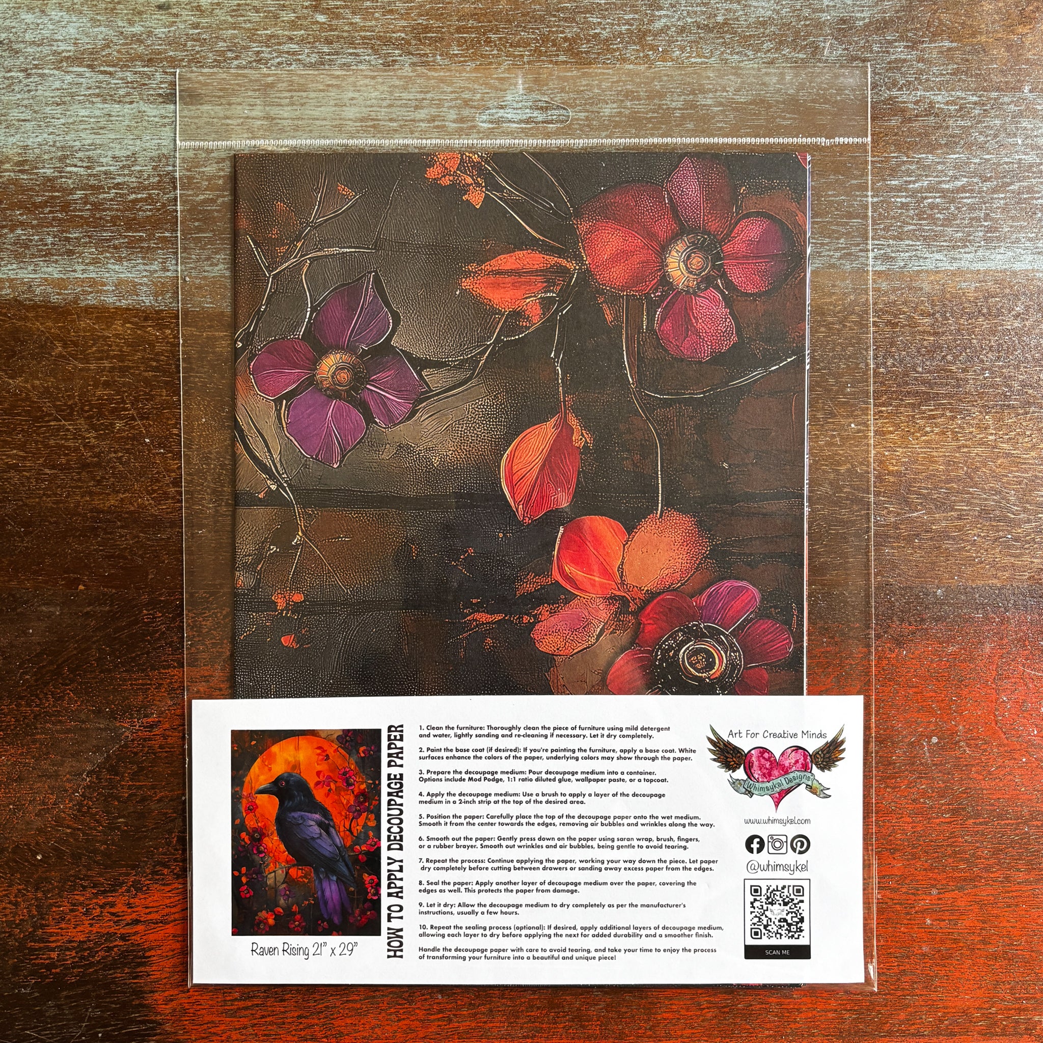 A package of Whimsykel's Raven Rising tissue paper is against a dark wood background.