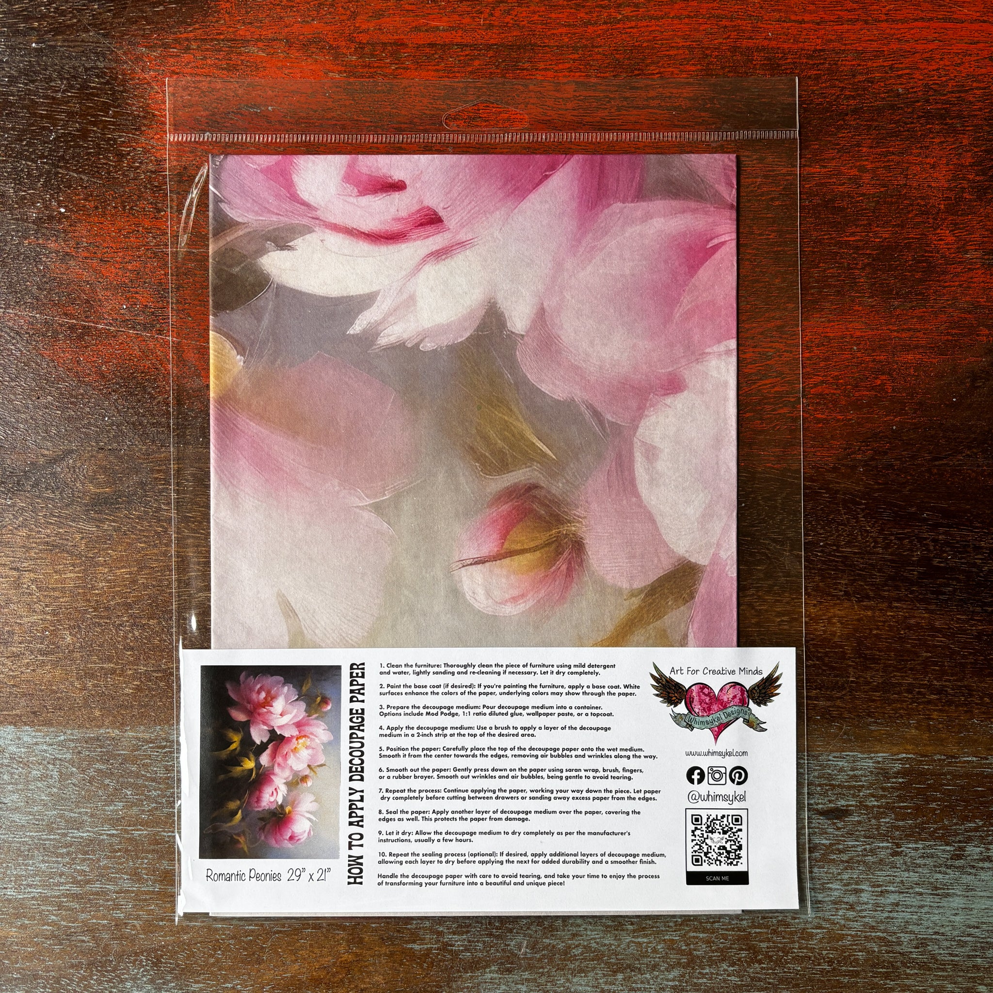 A package of Whimsykel's Romantic Peonies tissue paper is against a dark wood background.