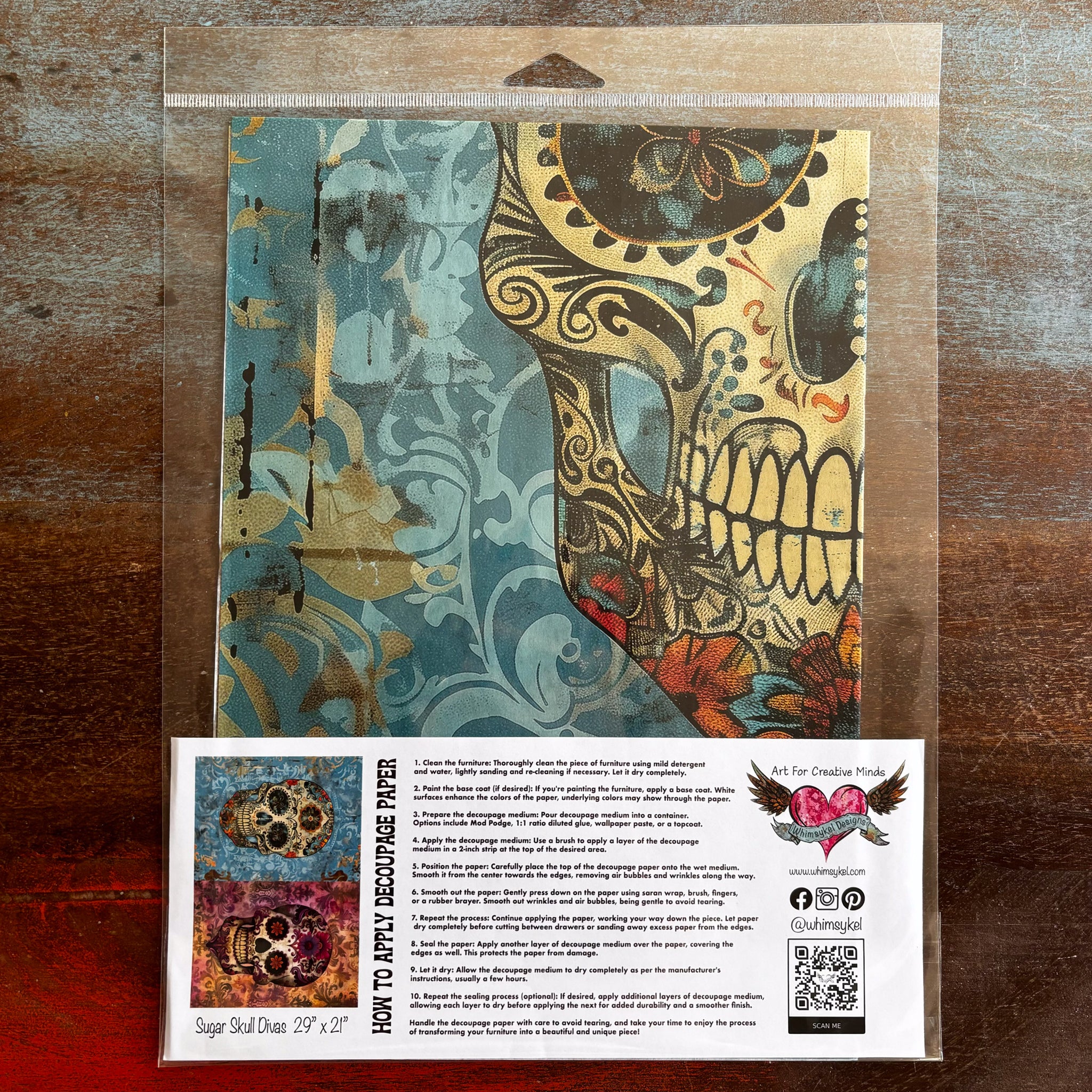 A package of Whimsykel's Sugar Skull Divas tissue paper is against a dark wood background.