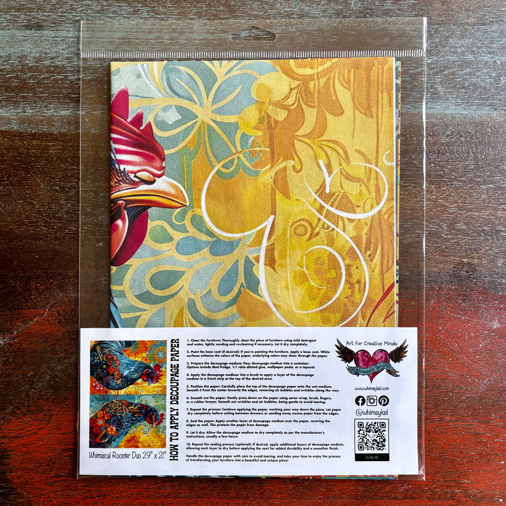 A package of Whimsykel's Whimsical Rooster Duo tissue paper is against a dark wood background.