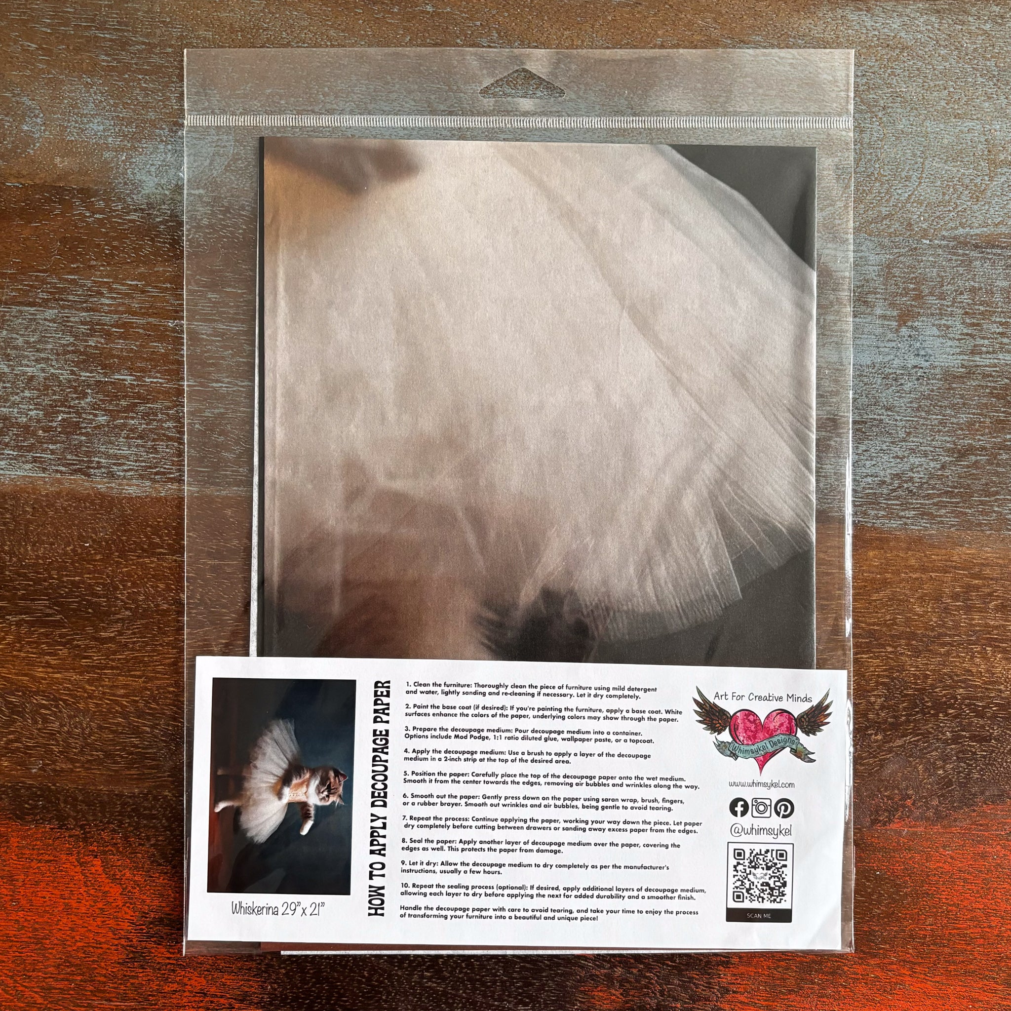 A package of Whimsykel's Whiskerina tissue paper is against a dark wood background.