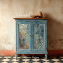 Vintage-style blue cabinet with floral panels against a textured wall, featuring the brand 'Whimsykel'.