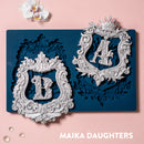 Zuri A&B monogram silicone mold with ornate frames and finished silver letter castings on pink background