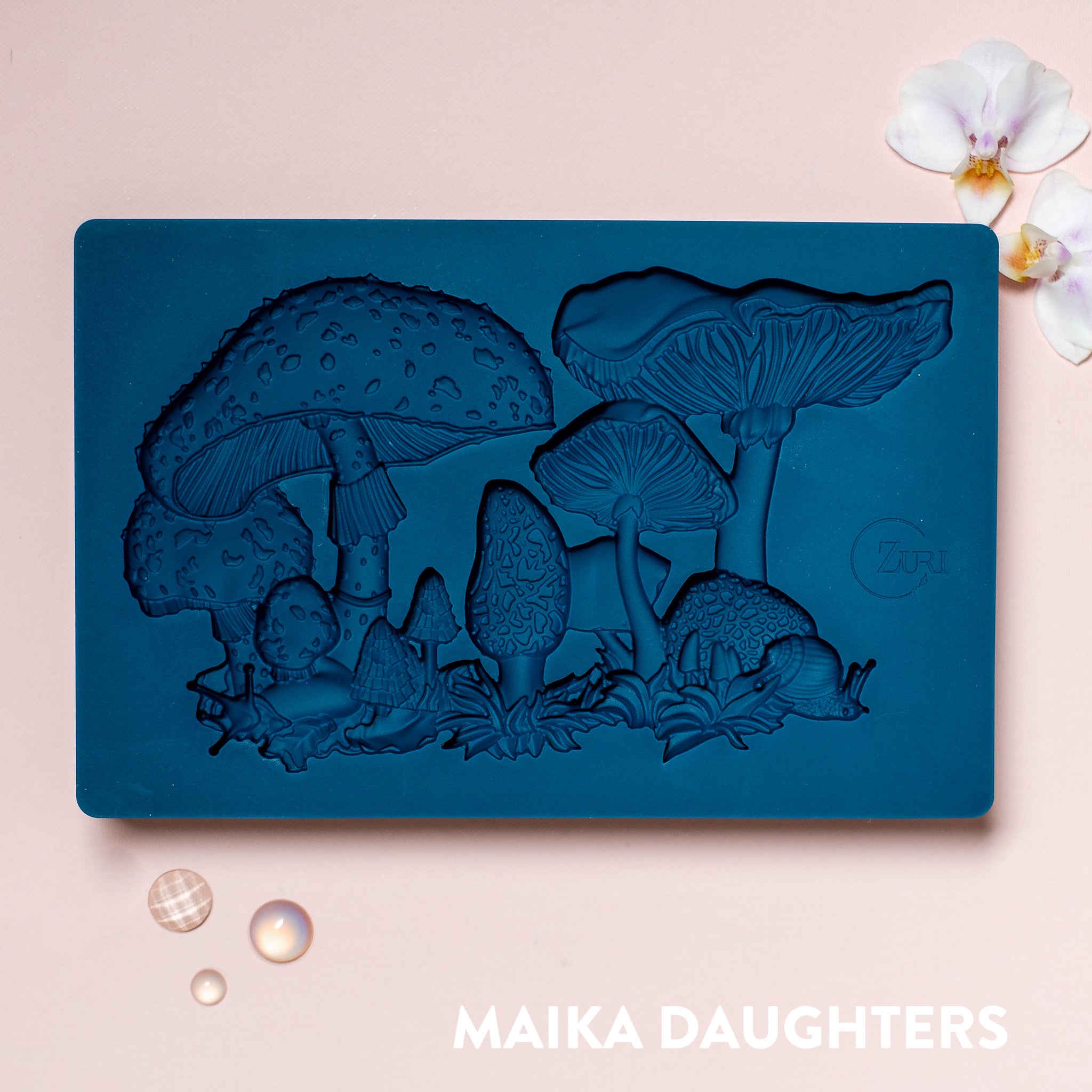 A blue silicone mold featuring a cluster of different kinds of mushrooms is against a light pink background.