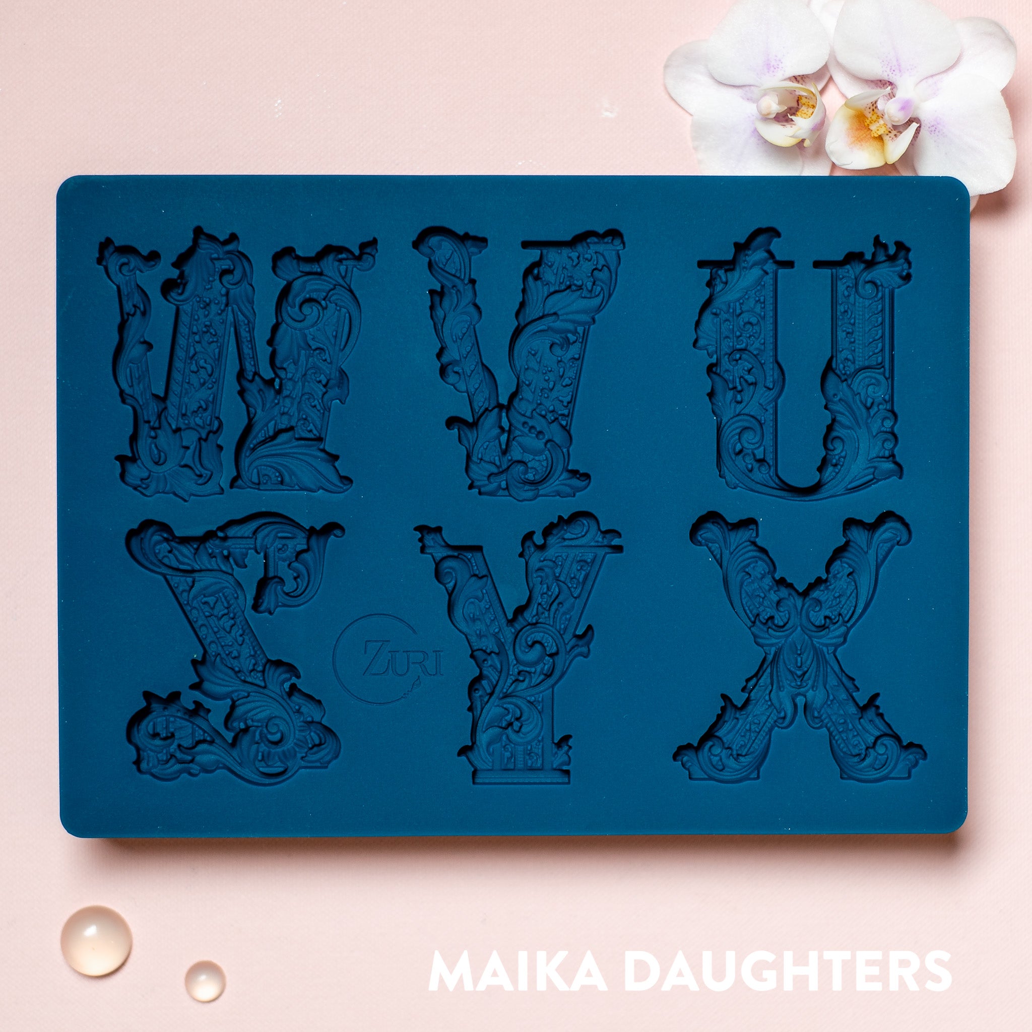 A blue silicone mold featuring 6 ornate letters of UVWXYZ are against a light pink background.