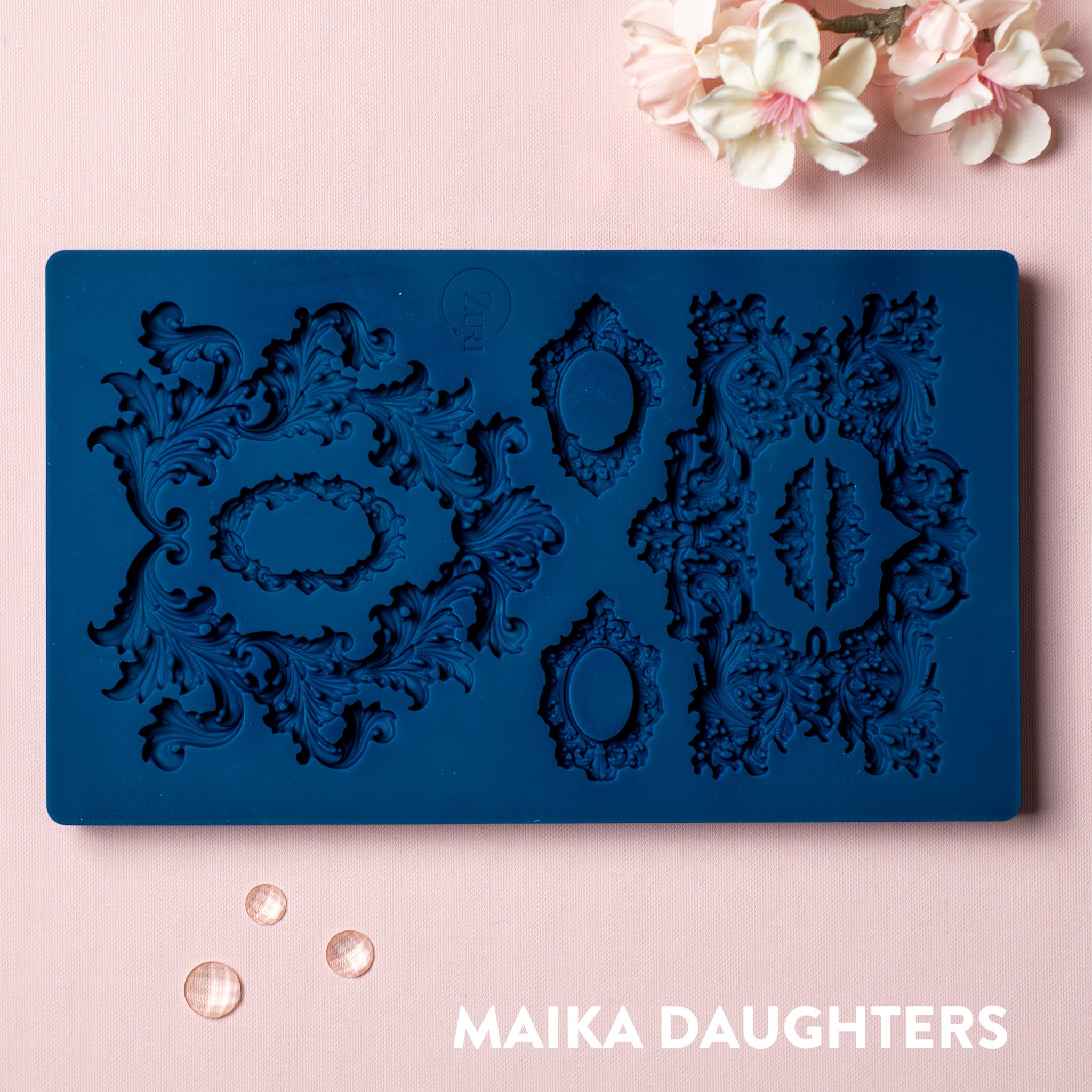 A blue silicone mold featuring 7 ornate frame is against a light pink background.