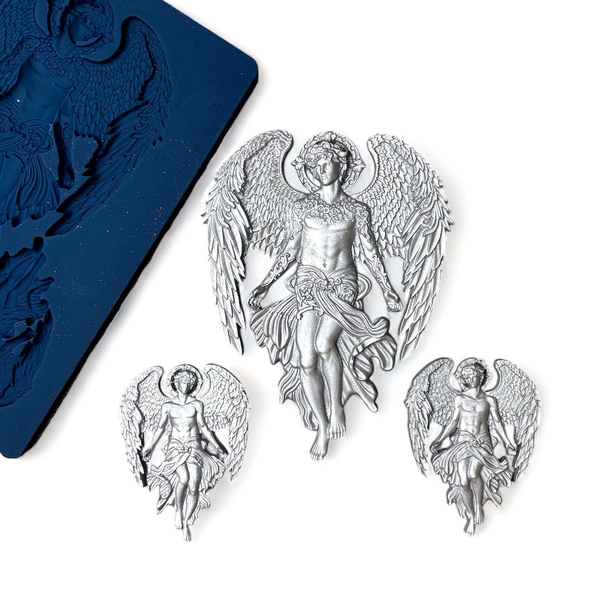 A blue silicone mold and silver colored castings of 1 large, and 2 small celestial angels with large wings are against a white background.