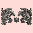 Silver colored silicone mold castings featuring 2 large gargoyle statues and a smaller gargoyle medallion are against a light pink background.