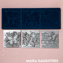 A blue silicone mold and silver colored castings of 3 tiles featuring butterflies, flowers and calligraphy are against a light pink background.