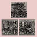 Silver colored castings of 3 tiles featuring butterflies, a lace border, and script writing are against a light pink background.