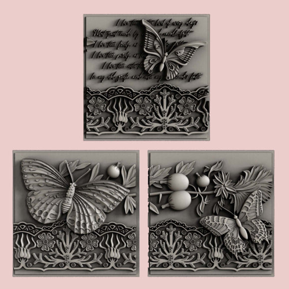 Silver colored castings of 3 tiles featuring butterflies, a lace border, and script writing are against a light pink background.